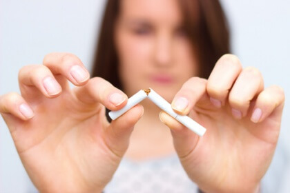 Nainen lopetta tupakoinnin ja katkaisee savukkeen