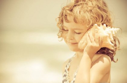 Tyttö kuuntelee simpukkaa