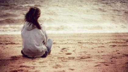 Nainen istuu rannalla