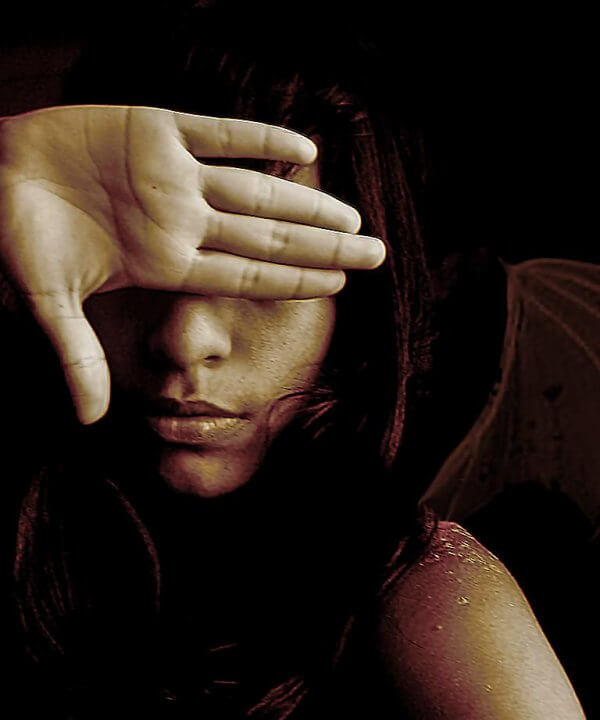 Nainen piiloutuu käden taa