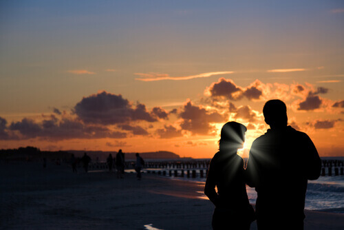pariskunta meren rannalla auringonlaskussa