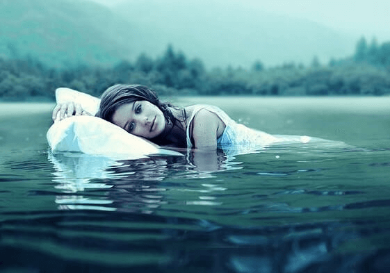 nainen kelluu vedessä tyynyn kanssa