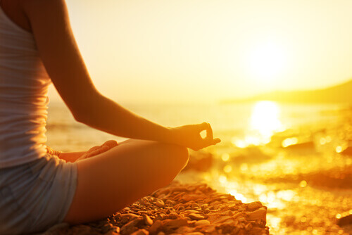 nainen meditoi rannalla