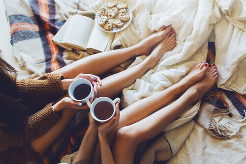 ystävät juovat teetä sängyssä