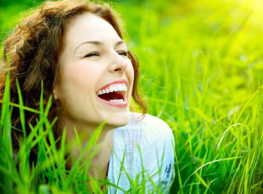 nainen nauraa nurmikolla