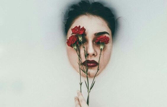 naisella kukkia kasvojen edessä