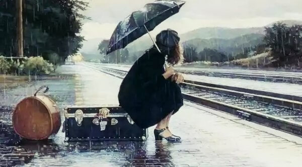 nainen odottaa junaa sateessa