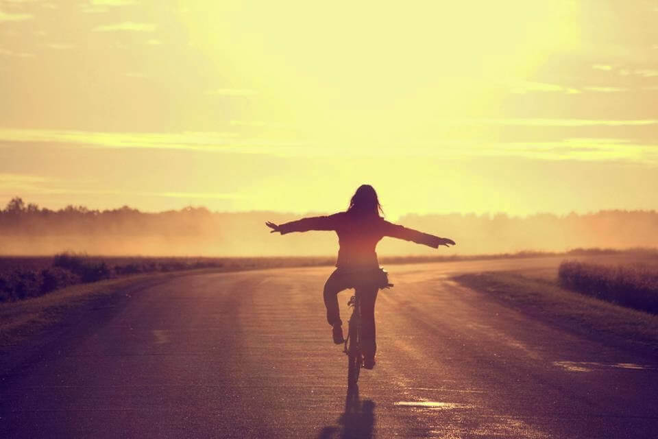 nainen ajaa pyörällä ilman käsiä