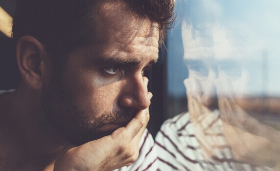 surullinen mies katsoo ulos ikkunasta