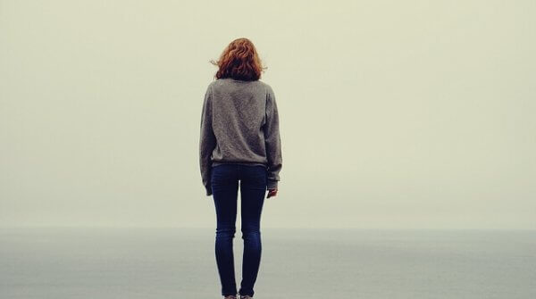 yksinäinen nainen katsoo merelle