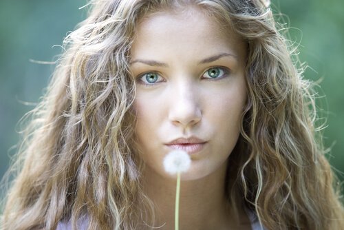 nainen puhaltaa voikukan