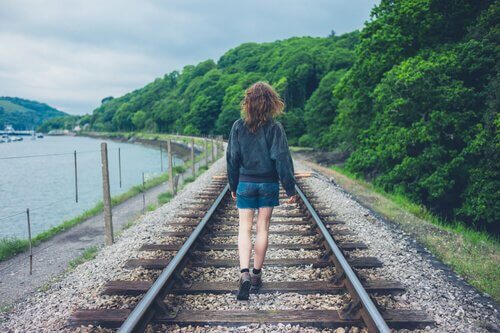 tyttö kävelee junanraiteilla