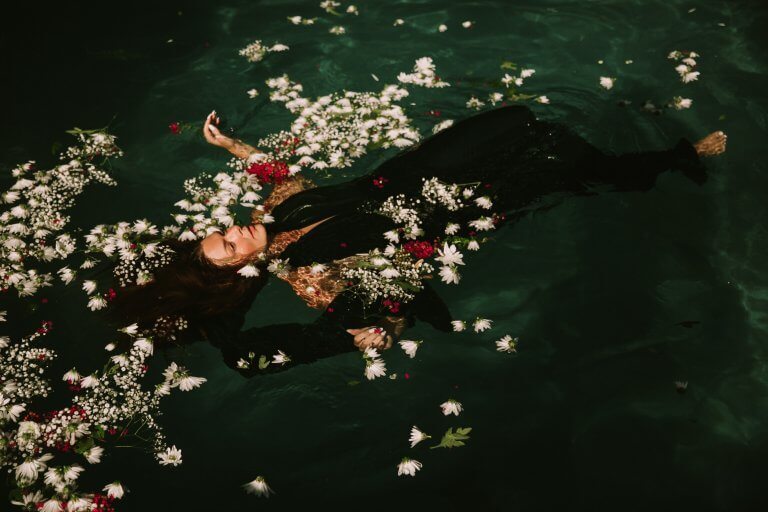 nainen ja kukat kelluvat vedessä
