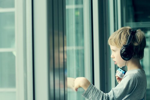 poika kuuntelee musiikkia ja katsoo ulos ikkunasta