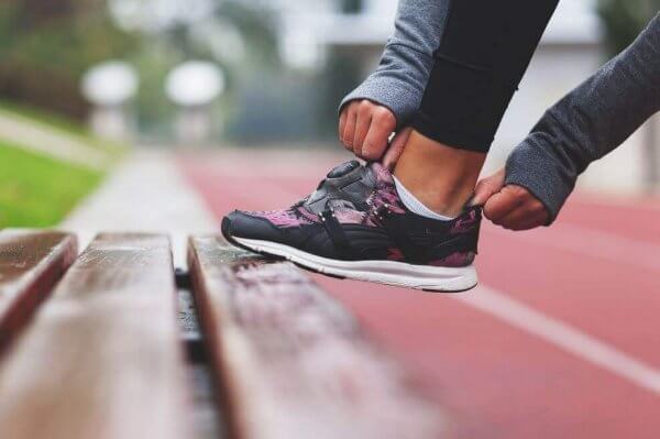 nainen vetää lenkkareita jalkaansa