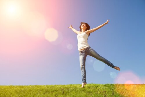 nainen hyppää onnellisena nurmikolla