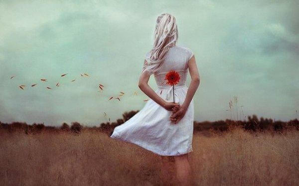 nainen kantaa kukkaa selkänsä takana