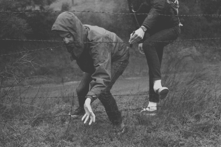 miehet käyttävät sinnikkyyttä päästäkseen aidan toiselle puolen