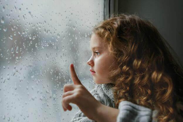 tyttö katselee ulos sateeseen
