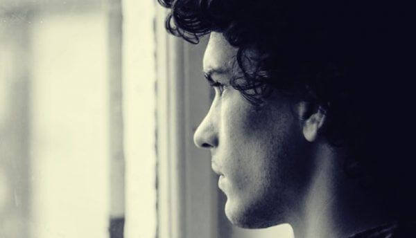 mies katsoo ikkunasta ulos