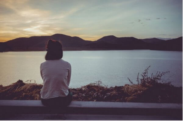 nainen istuu ja katsoo järvelle