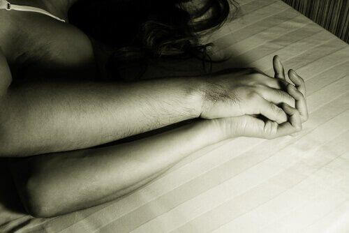 pariskunta pitää käsistä kiinni sängyssä