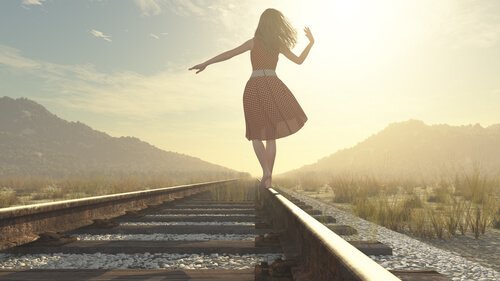 nainen kävelee rautatiekiskoilla