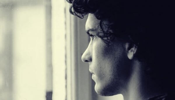 mies katsoo ikkunasta ulos