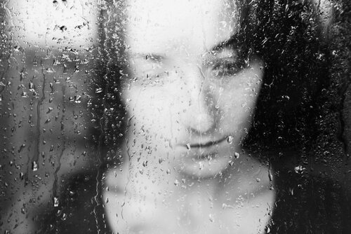 nainen sateisen ikkunan takana