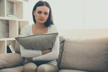 nainen halaa tyynyä sohvalla