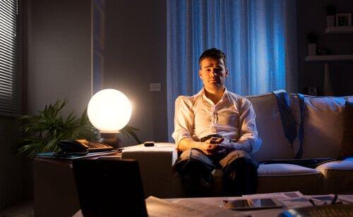 mies istuu sohvalla keskellä yötä