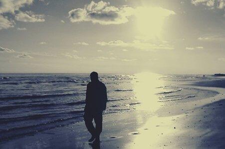 mies kävelee yksin rannalla