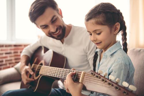 isä opettaa tytärtään soittamaan kitaraa, mutta tekeekö musiikki lapsista älykkäämpiä?