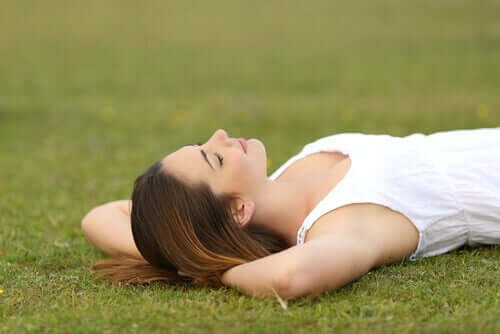 nainen makaa nurmikolla, sillä hänellä on tasapaino työelämässä