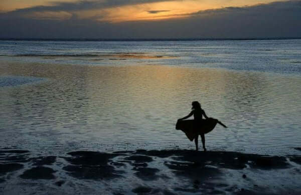 Nainen on yksin rannalla auringonlaskussa.